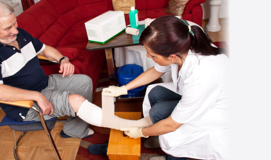 caregiver dressing an old man's wounds