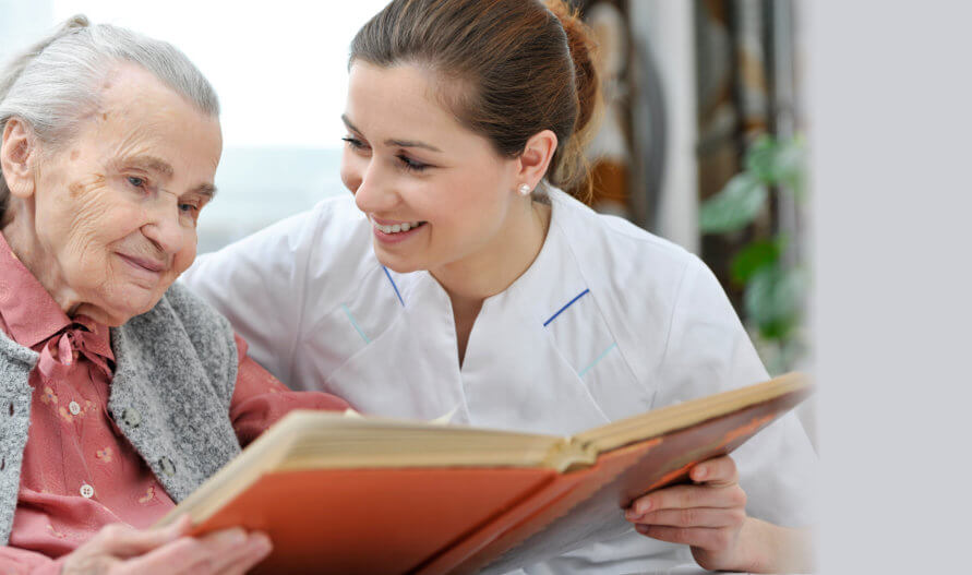 caregiver reading a book to her old patient